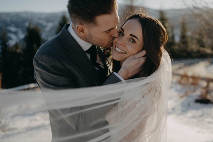 Glückliches Brautpaar mit wehenden Schleier im Winterlicht – Hochzeitsfotograf Kärnten